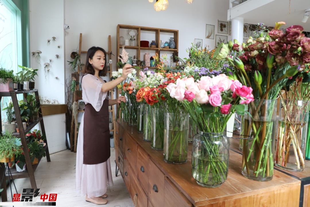 王黎媛是一名河南姑娘，在昆明念完大學(xué)后，就再也舍不下春城的藍(lán)天陽光、青山碧水，更舍不下這里的四時繁花，于是就干脆留了下來，成了一名媒體人。2017年的時候又毅然辭去工作，創(chuàng)業(yè)開起了花店，成了都市里的一名“花房姑娘”。圖為王黎媛在自己的花店中整理鮮花。新華網(wǎng) 周亞平/攝 念新洪/文